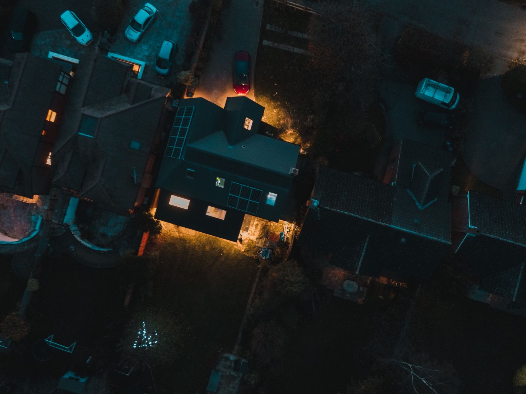 Solar motion security light mounted on a house wall lighting a driveway at night