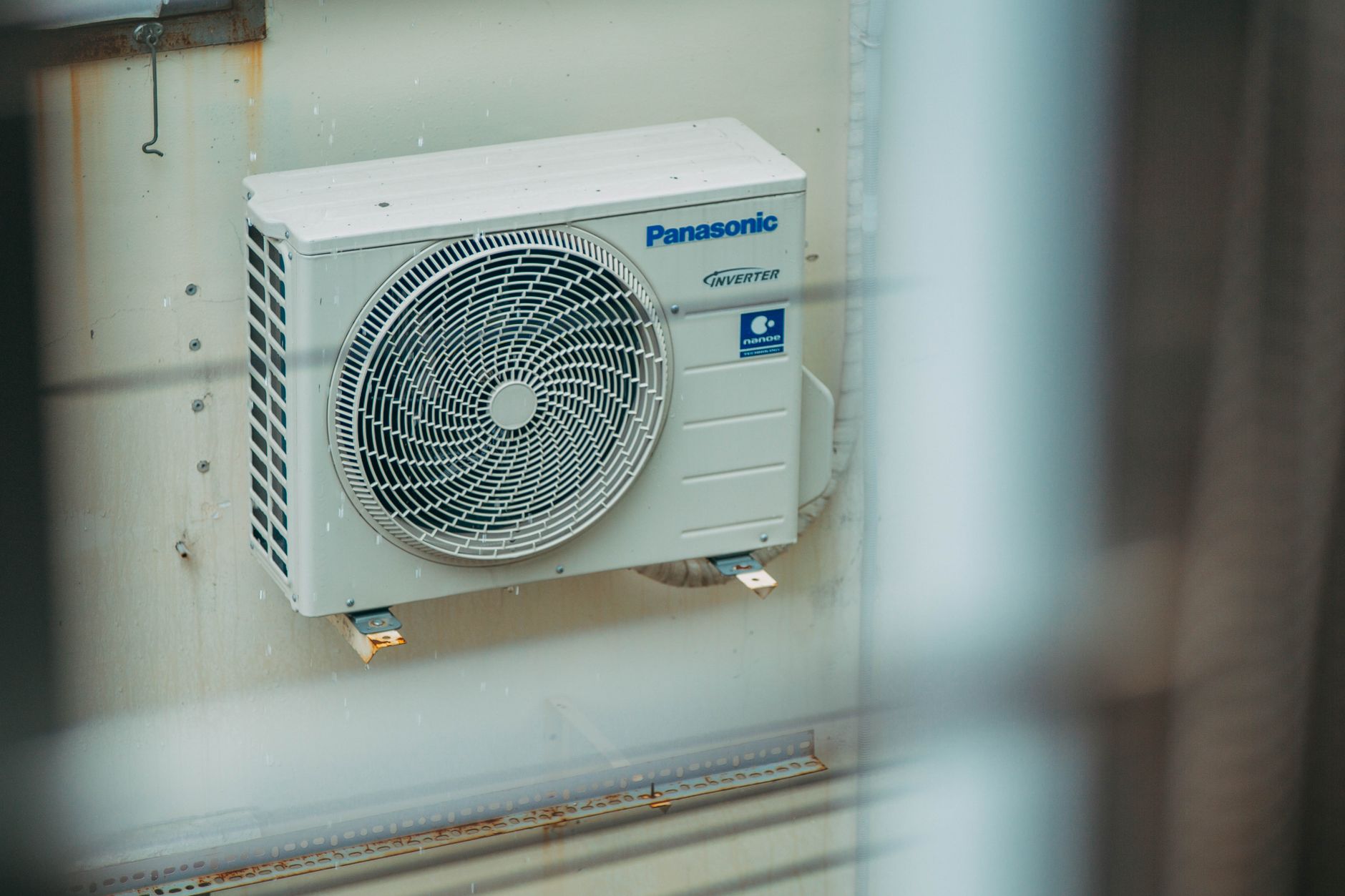 Outdoor air source heat pump unit installed next to a house wall