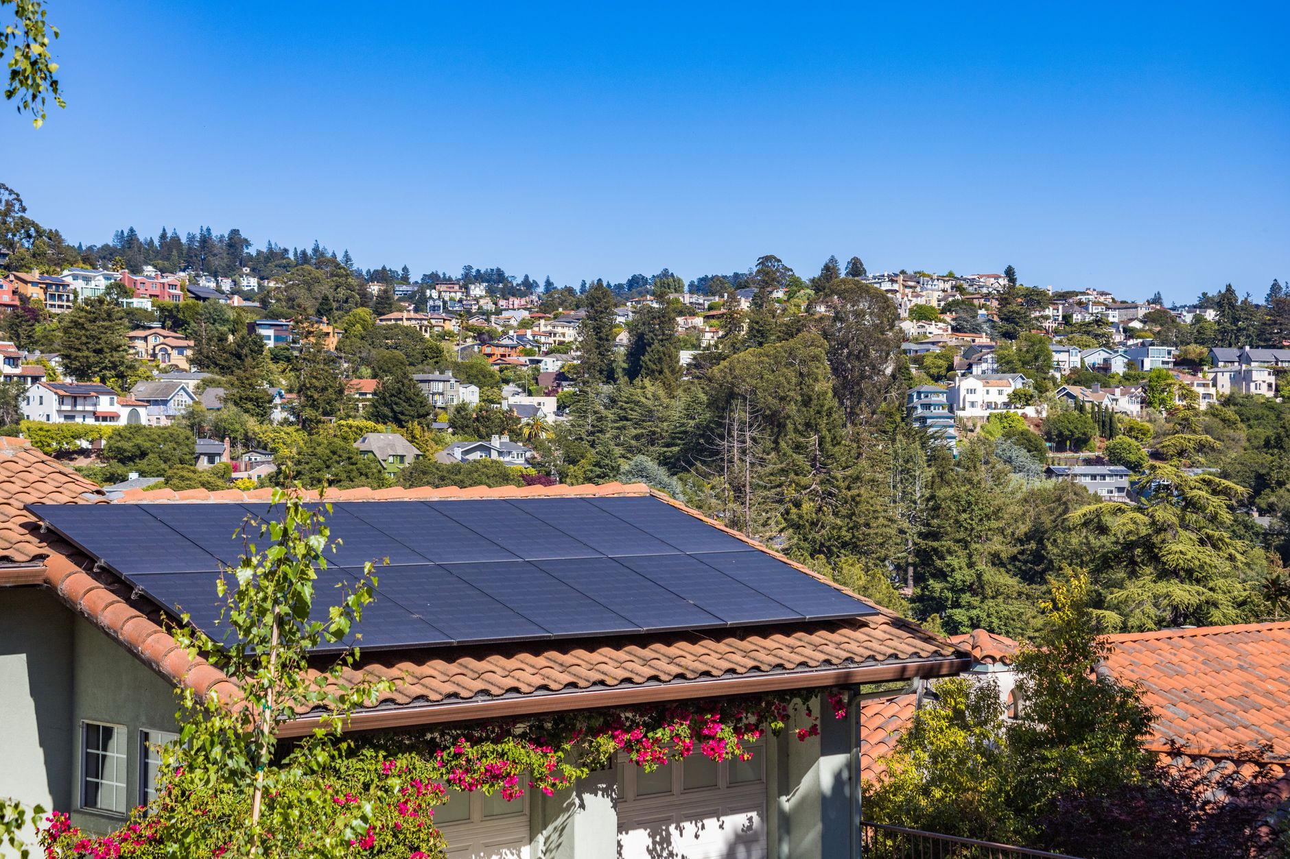 Rooftop solar panels installed on a suburban house with a clear blue sky