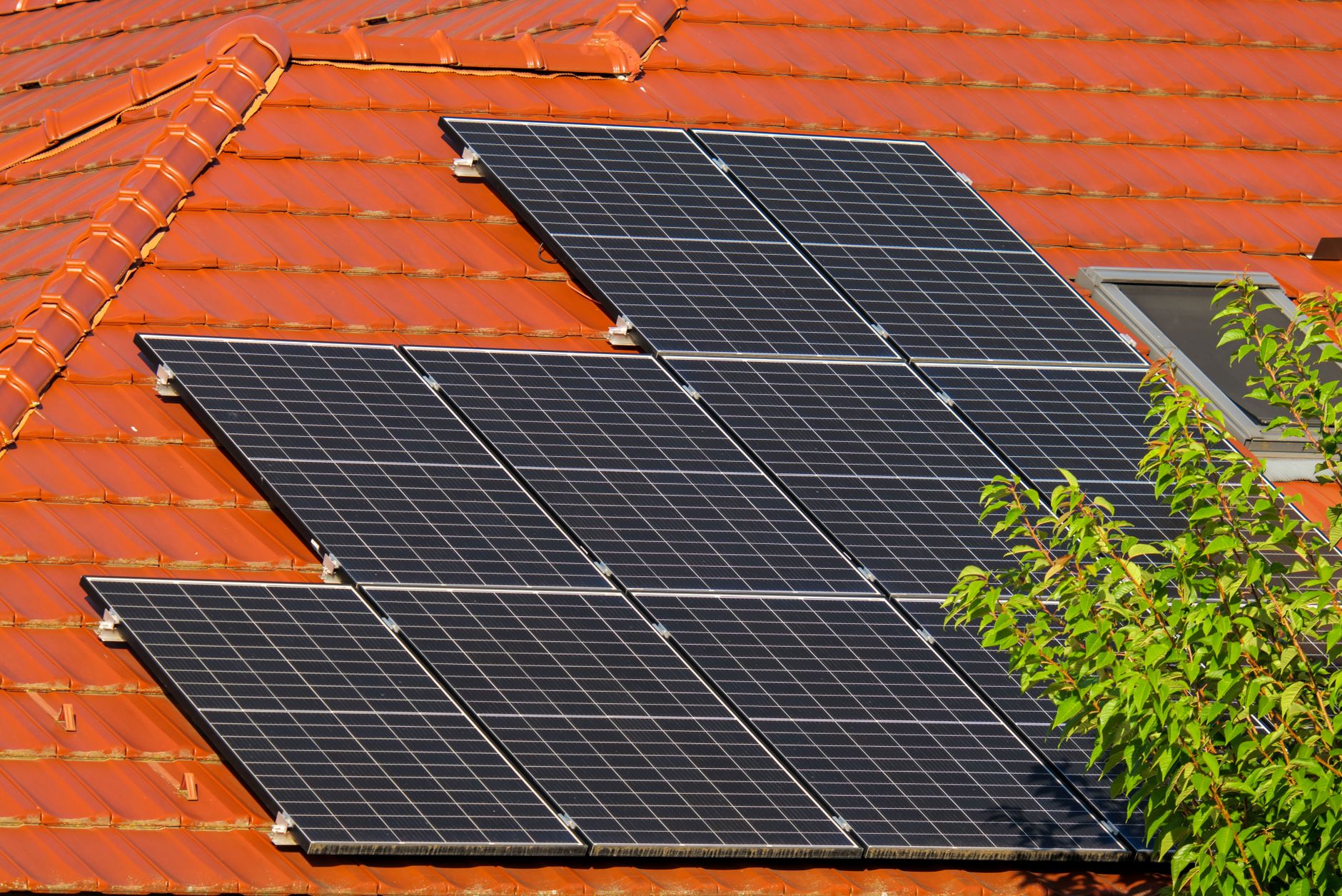 A residential roof covered with black solar panels under bright sunlight
