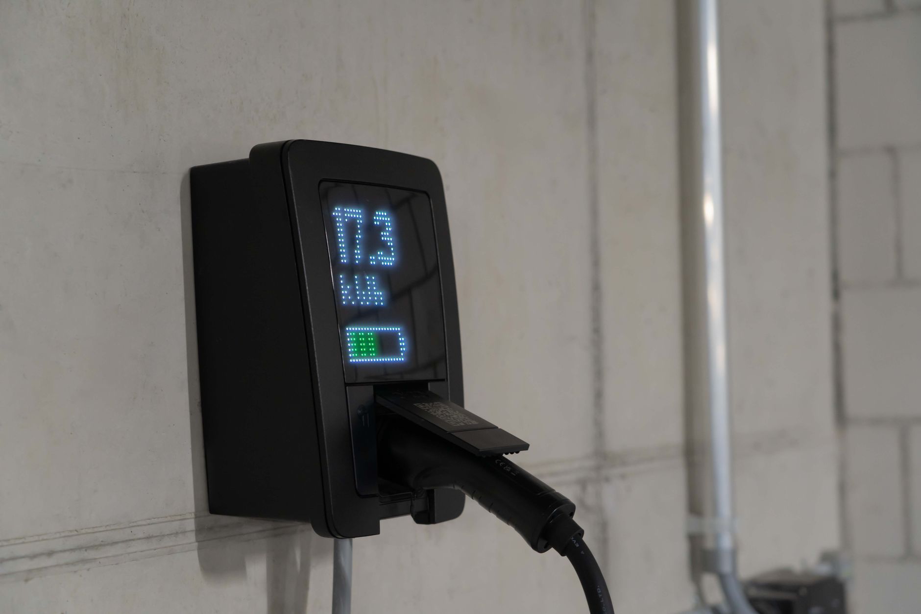 A home battery backup system mounted on a clean garage wall next to an electrical panel