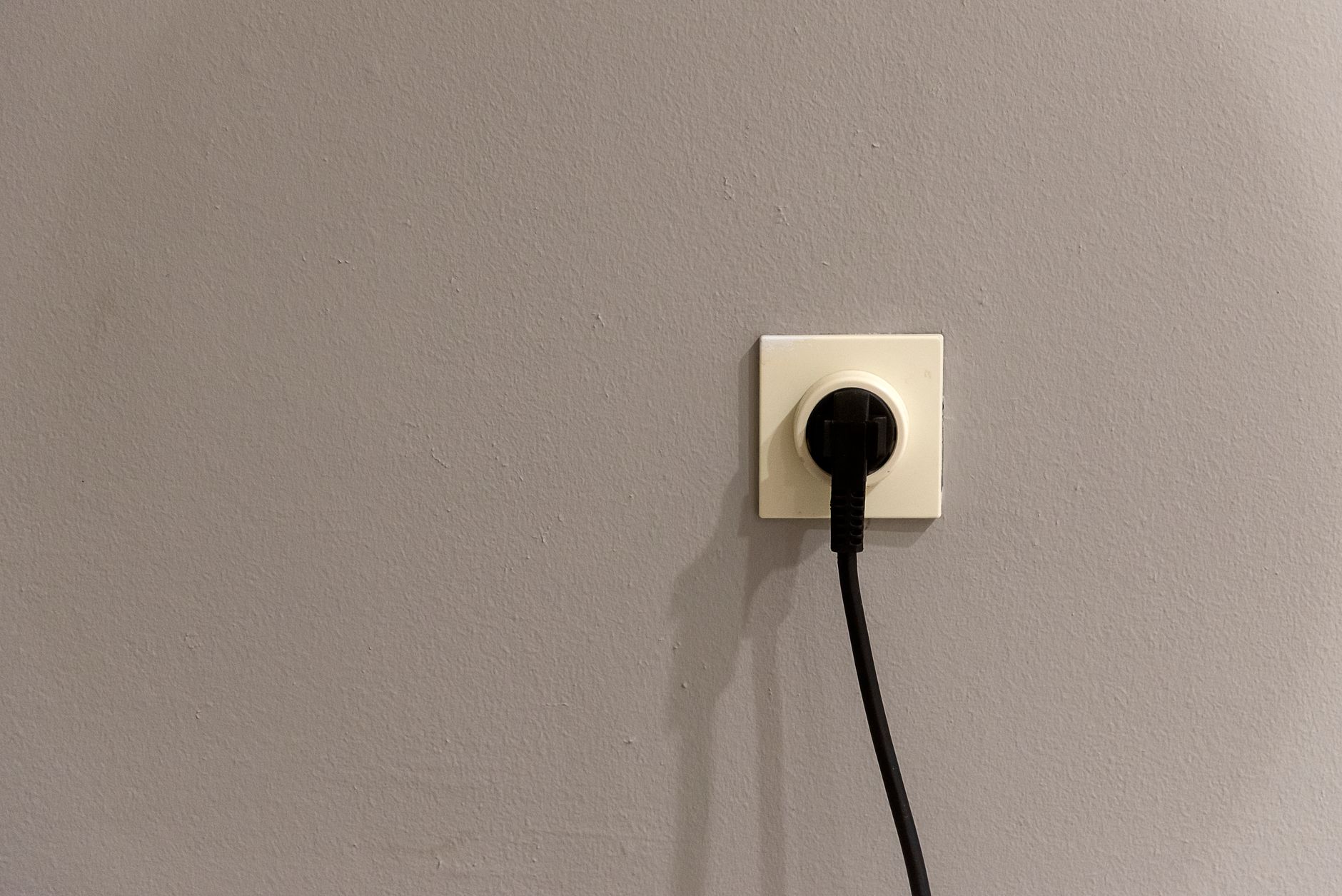 A homeowner plugging a Kill A Watt meter into a wall outlet to measure appliance energy use