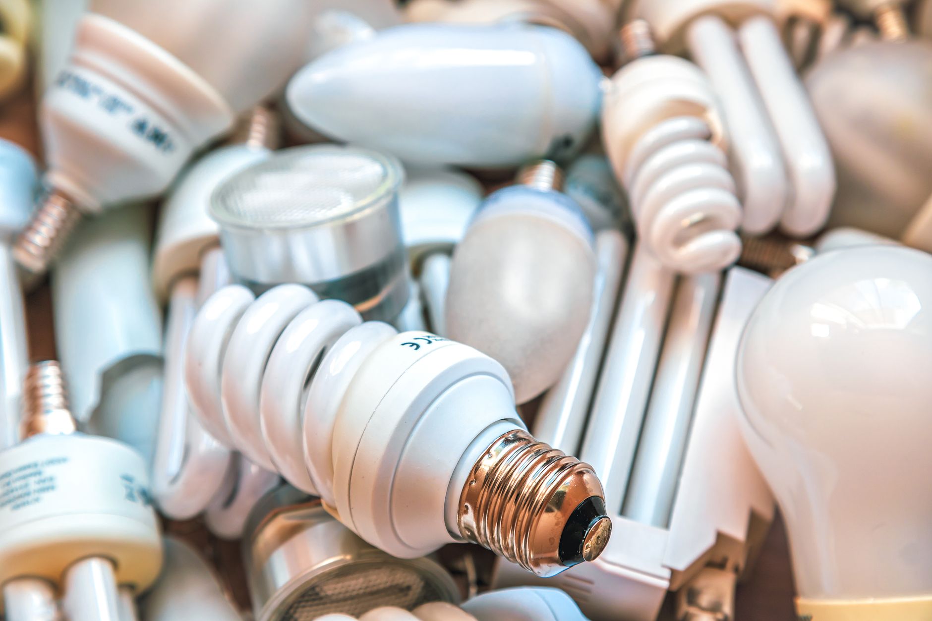 A hand screwing an LED bulb into a ceiling light fixture in a modern kitchen