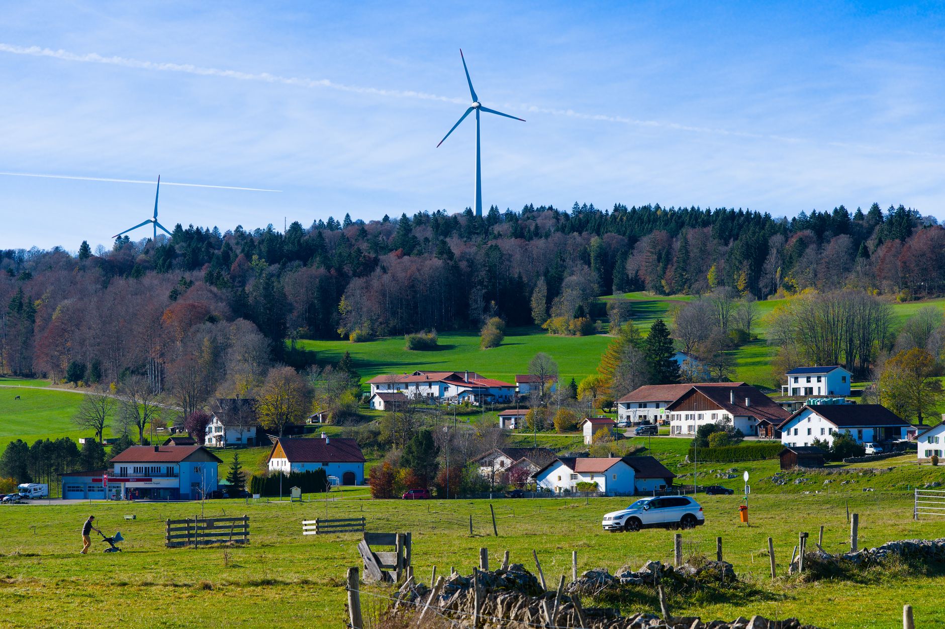 Small wind turbine on a tall tower beside a rural home