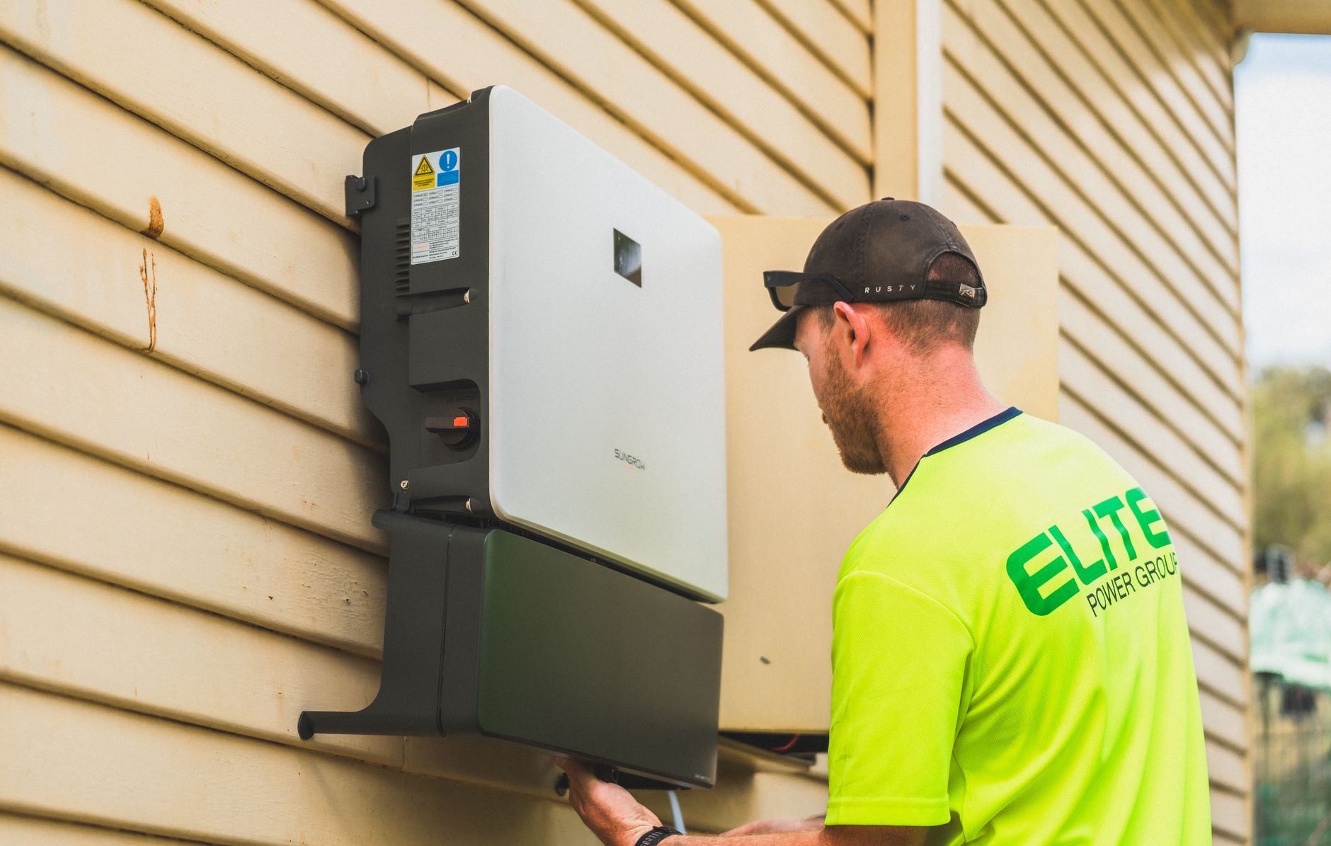 White Tesla Powerwall 3 battery mounted on a garage wall next to an electrical panel.